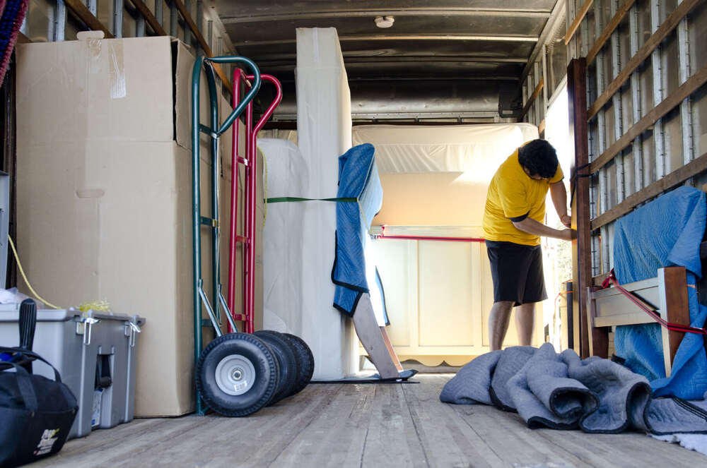 Furniture wrapped in moving blankets and strapped securely inside the SpaceMan Moving truck