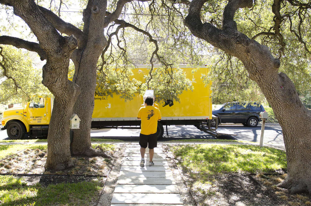 SpaceMan mover carrying a box up a walkway in a South Austin neighborhood