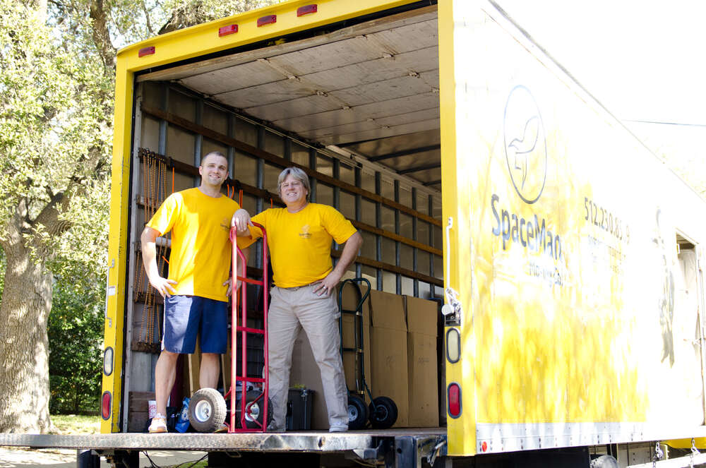 Founders Nowell Maluski Jr. and Nowell Maluski Sr. standing in the back of the open SpaceMan Moving truck